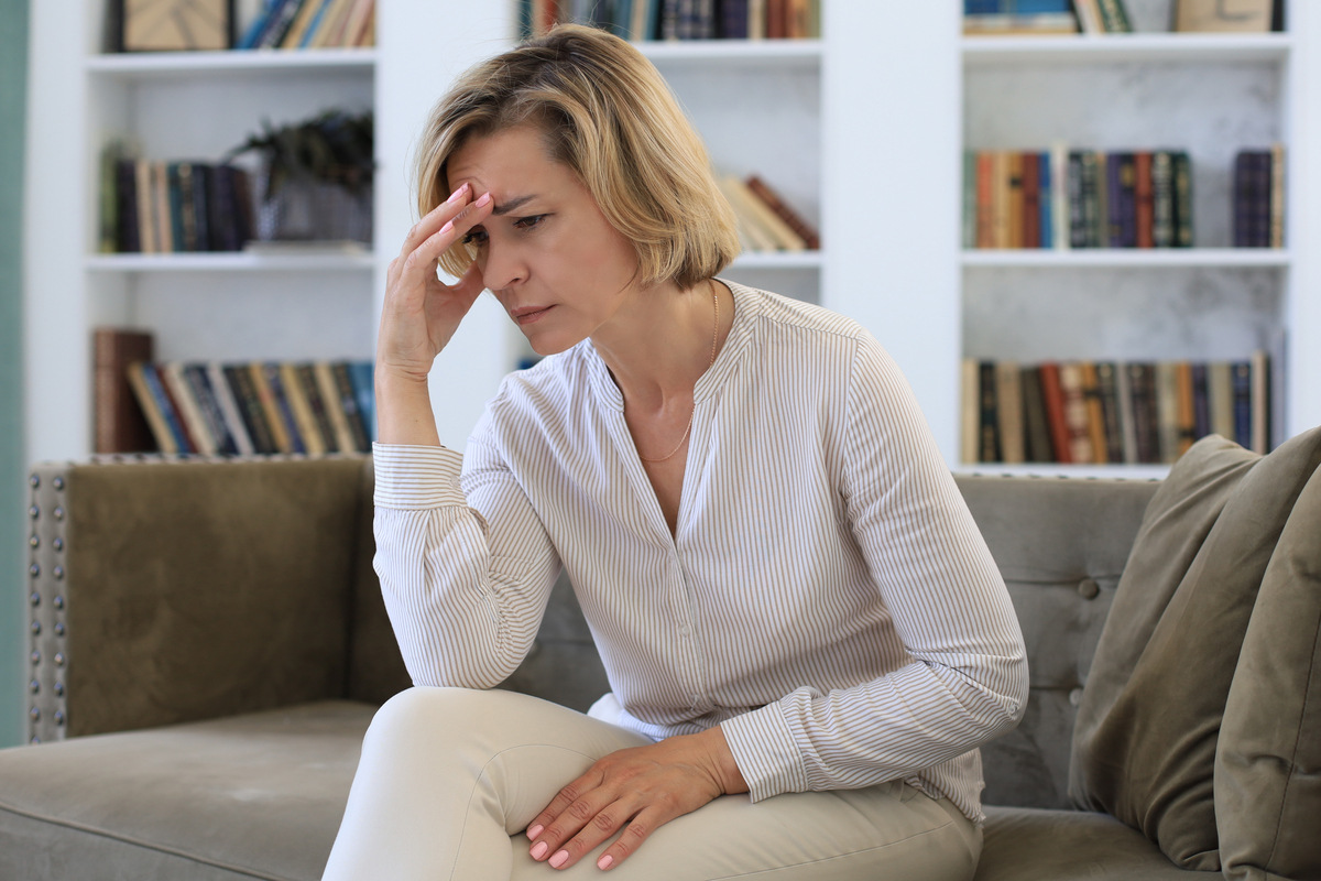 Woman sitting on couch experiencing HRT and anxiety symptoms during menopause