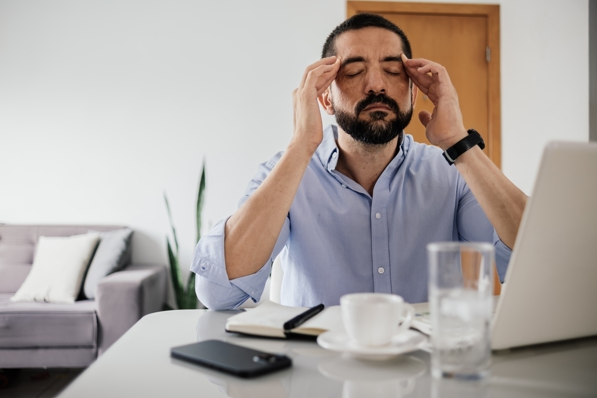 Man struggling with low testosterone brain fog rubbing his temples at his desk